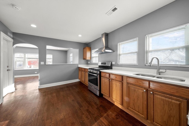 kitchen featuring dark wood-type flooring, wall chimney range hood, sink, plenty of natural light, and stainless steel range with gas stovetop