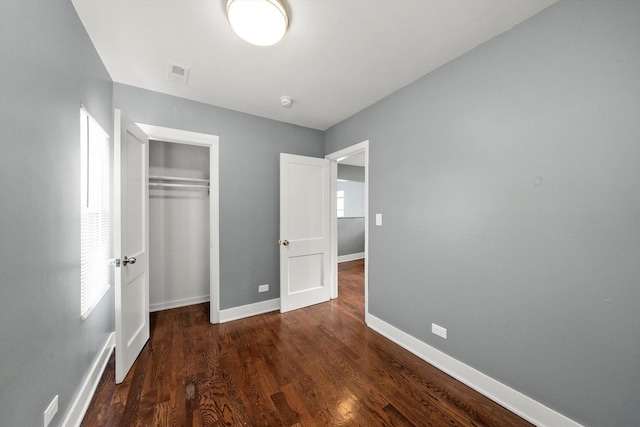 unfurnished bedroom featuring dark hardwood / wood-style flooring and a closet