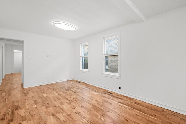 unfurnished room featuring beam ceiling and light wood-type flooring