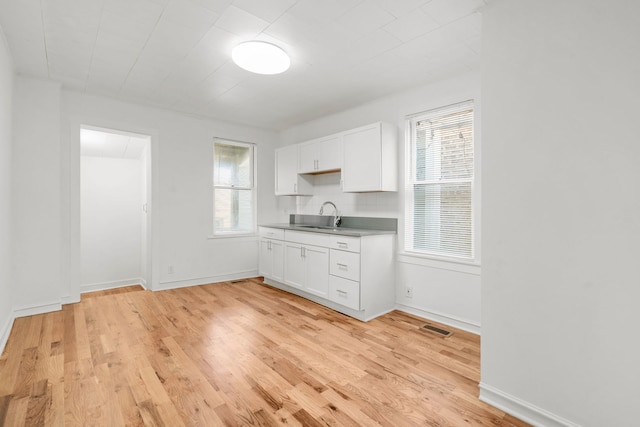 kitchen featuring light hardwood / wood-style flooring, white cabinetry, a wealth of natural light, and sink