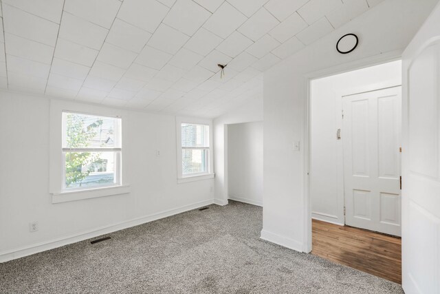 carpeted spare room with vaulted ceiling