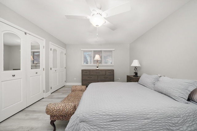 bedroom featuring light wood-type flooring, two closets, and ceiling fan