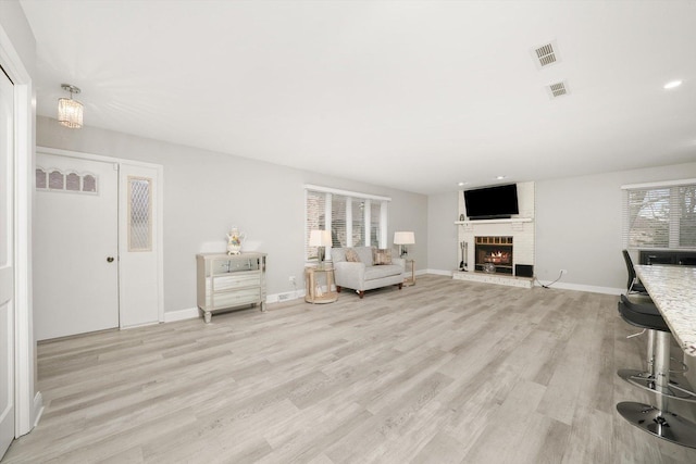 unfurnished living room featuring light wood-type flooring and a brick fireplace