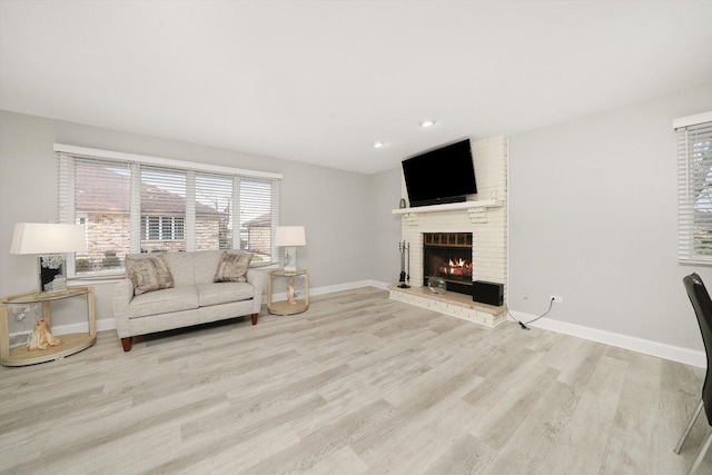 living room with light hardwood / wood-style floors and a brick fireplace