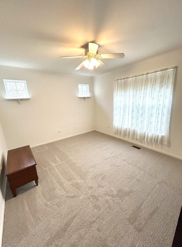 carpeted empty room with visible vents, ceiling fan, and baseboards