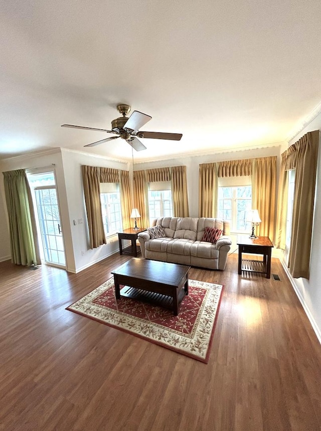 living area featuring plenty of natural light, wood finished floors, baseboards, and ornamental molding