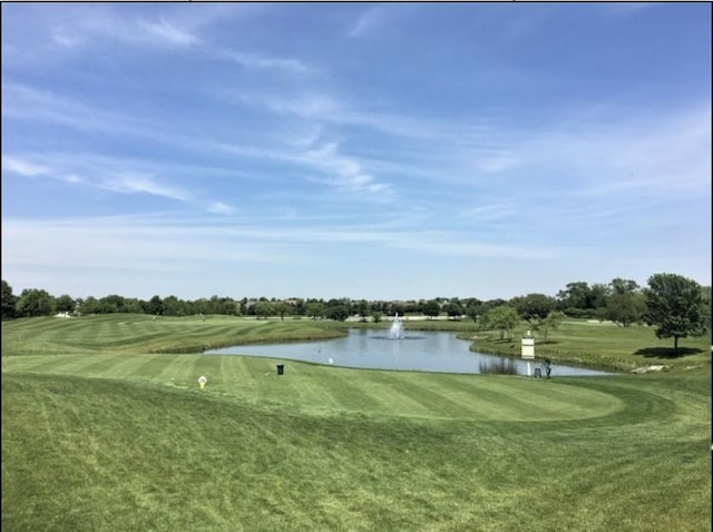 view of property's community with golf course view, a water view, and a yard