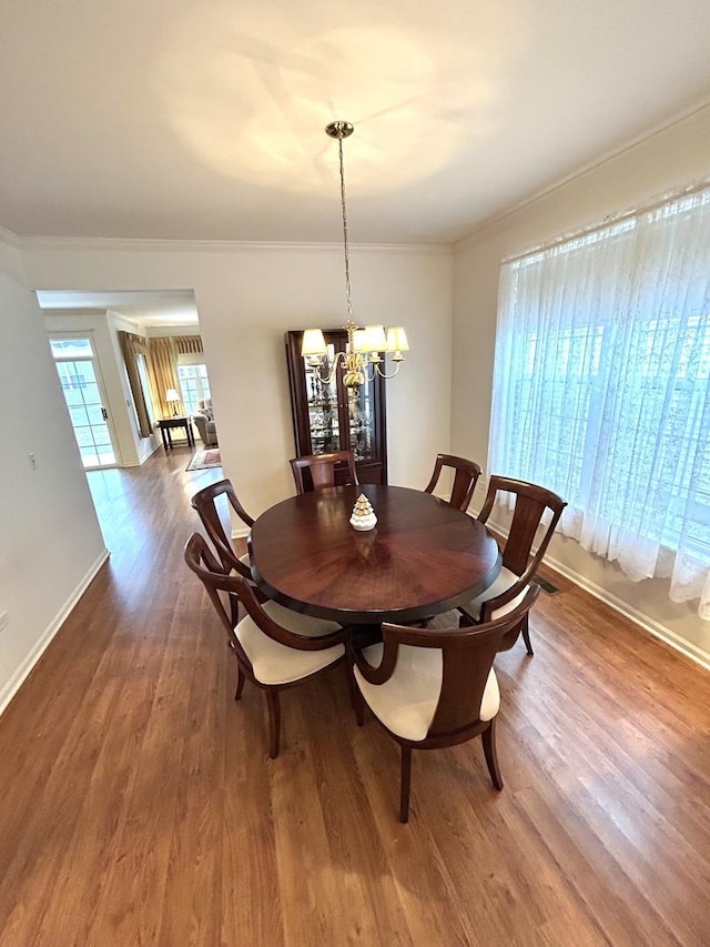 dining room with crown molding, a notable chandelier, wood finished floors, and baseboards