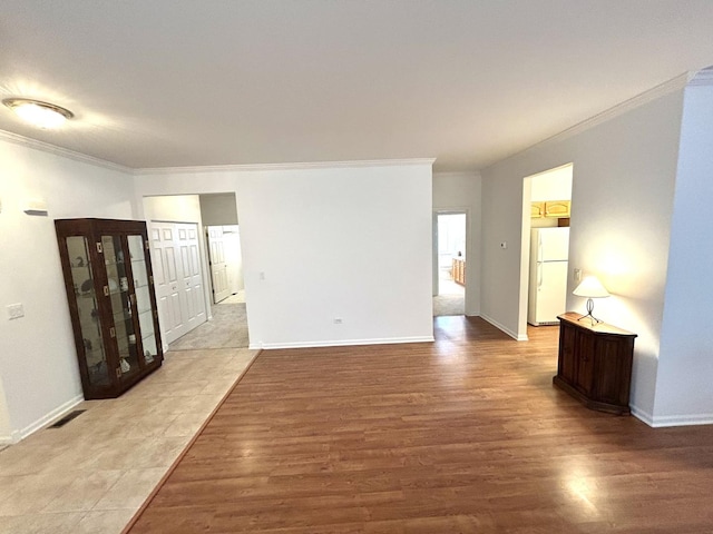 unfurnished room with crown molding, wood finished floors, visible vents, and baseboards