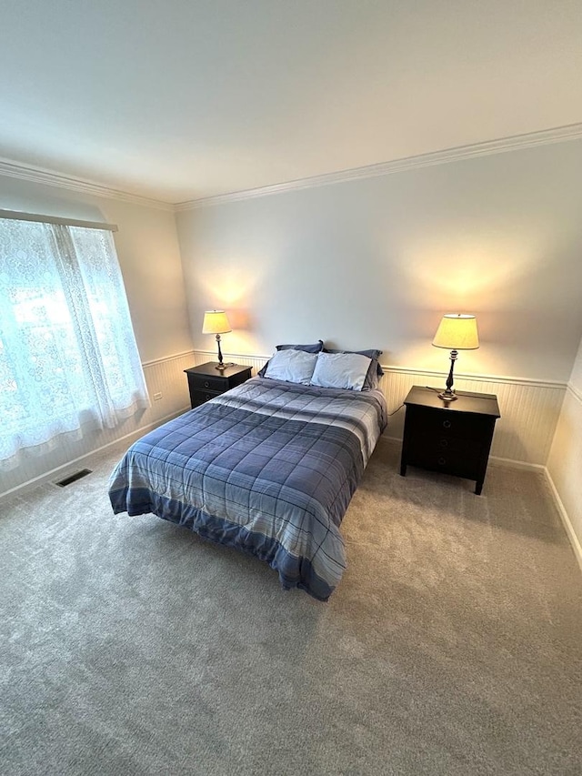 bedroom featuring visible vents, a wainscoted wall, ornamental molding, carpet, and wooden walls