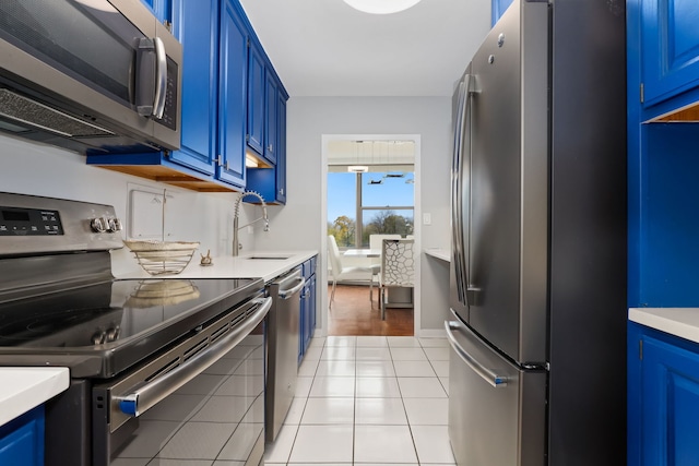 kitchen with light tile patterned flooring, sink, blue cabinetry, and appliances with stainless steel finishes