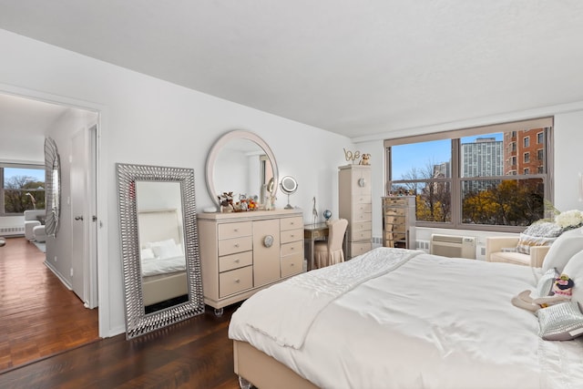 bedroom with a wall unit AC and dark wood-type flooring