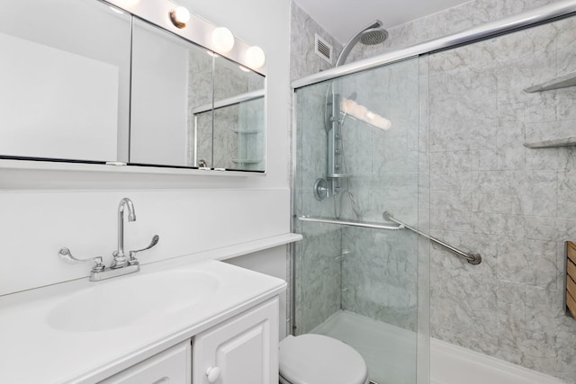 bathroom featuring vanity, toilet, and a shower with shower door