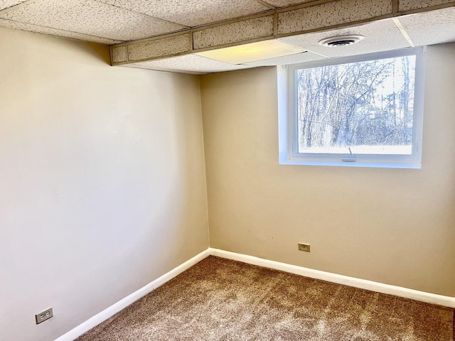 basement featuring a paneled ceiling and carpet