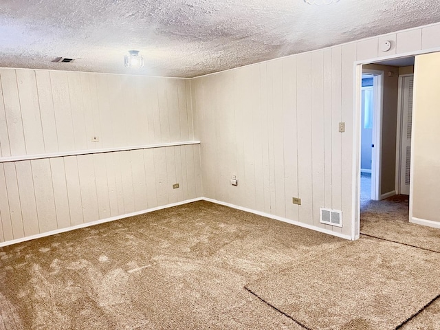 carpeted spare room featuring wood walls