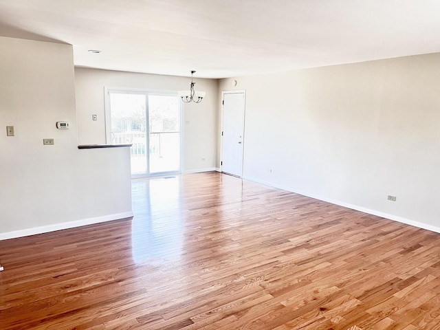 spare room featuring light hardwood / wood-style floors and a notable chandelier