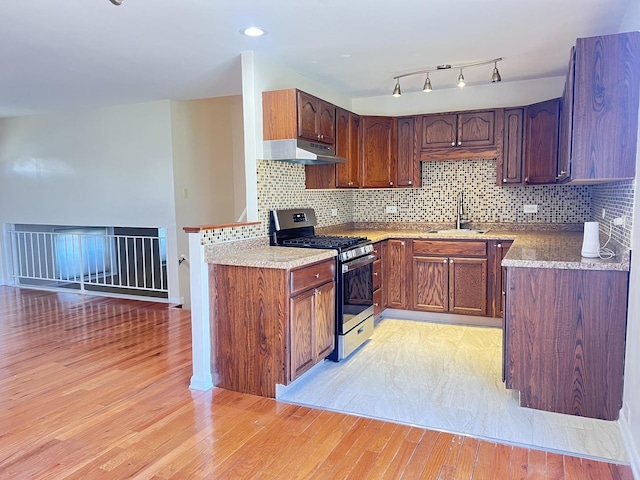 kitchen featuring light wood-type flooring, gas stove, backsplash, and sink