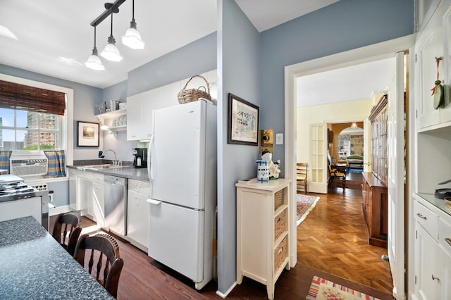 kitchen featuring white cabinets, sink, hanging light fixtures, stainless steel dishwasher, and white fridge