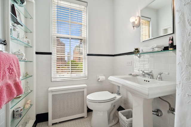 bathroom featuring toilet, tile walls, and radiator