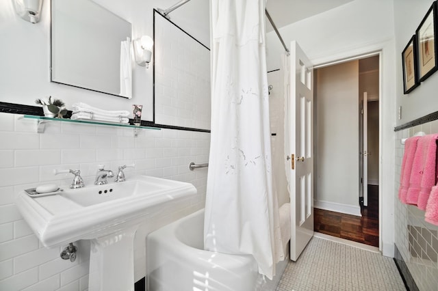 bathroom featuring sink, tile patterned floors, shower / bathtub combination with curtain, and tile walls