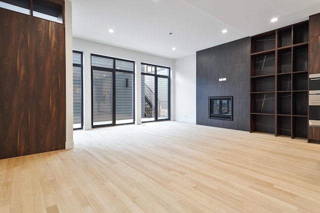 unfurnished living room with a large fireplace and light wood-type flooring