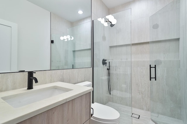 bathroom featuring vanity, toilet, tile walls, and a shower with shower door