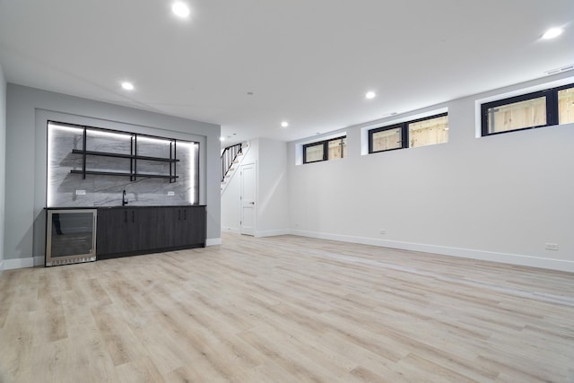 unfurnished living room featuring light hardwood / wood-style floors, sink, and beverage cooler