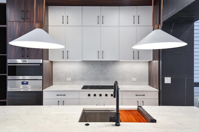 kitchen with double oven, decorative backsplash, white cabinets, and light stone countertops