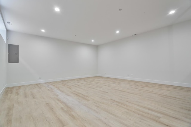 empty room with electric panel and light hardwood / wood-style floors