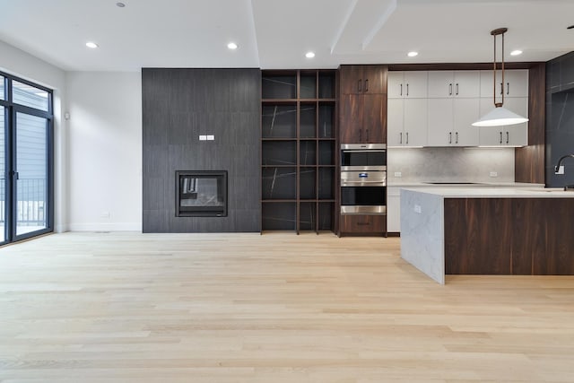 kitchen with tasteful backsplash, a wealth of natural light, light hardwood / wood-style floors, and decorative light fixtures