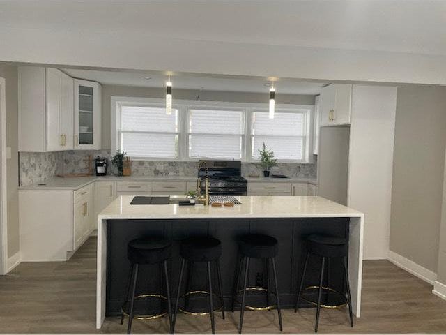 kitchen featuring white cabinets, a kitchen island, a wealth of natural light, and black stove