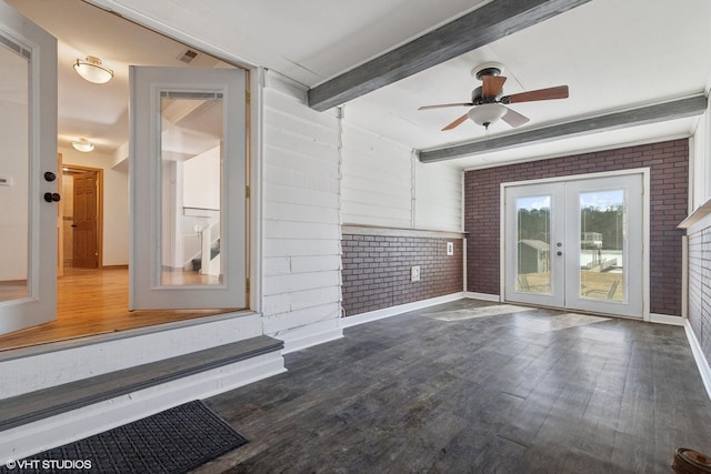 spare room with french doors, beamed ceiling, brick wall, and wood finished floors