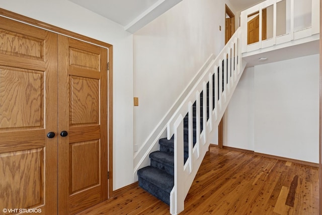 staircase featuring wood-type flooring and baseboards