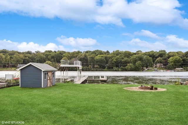 view of yard with a storage shed, an outdoor fire pit, a boat dock, a water view, and an outdoor structure