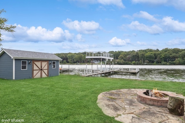 view of yard with an outdoor fire pit, a dock, a water view, an outdoor structure, and a shed