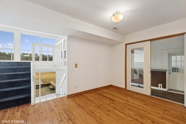 spare room featuring visible vents, stairway, hardwood / wood-style flooring, and baseboards