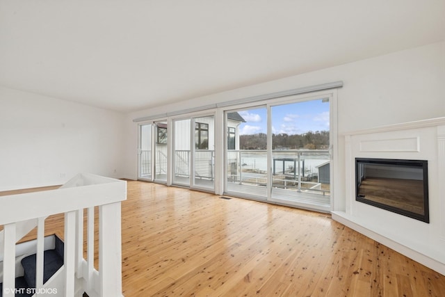 unfurnished living room with visible vents, a glass covered fireplace, and light wood-style flooring