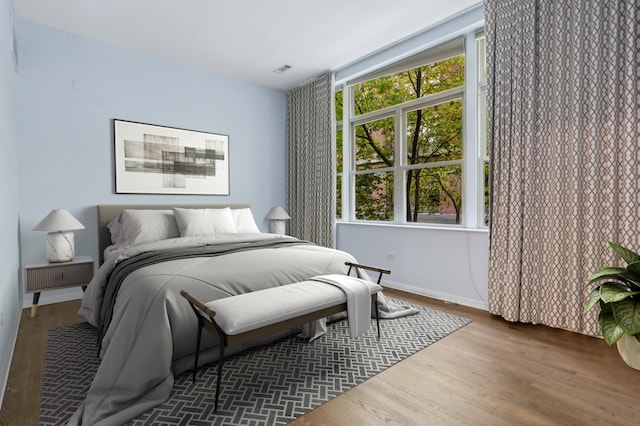 bedroom with dark hardwood / wood-style floors and multiple windows