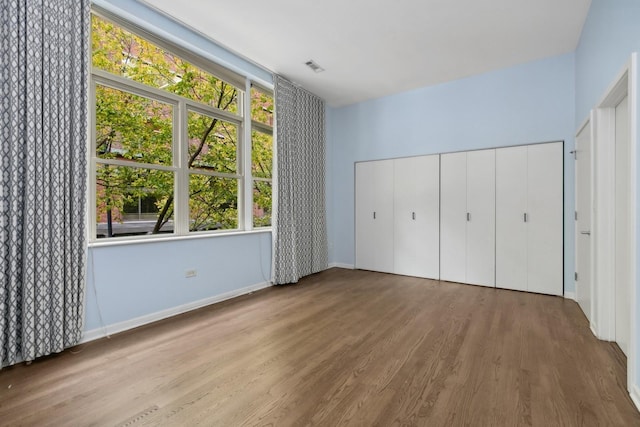 unfurnished bedroom featuring a closet, light wood-type flooring, and multiple windows