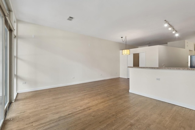 unfurnished living room with lofted ceiling, light hardwood / wood-style floors, and track lighting