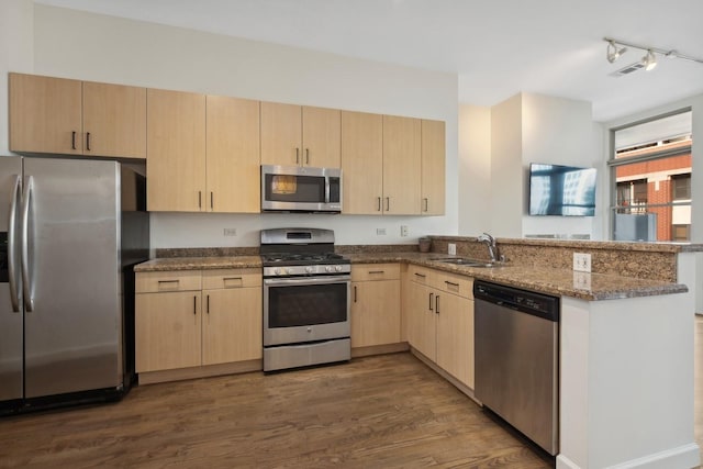 kitchen featuring light brown cabinets, sink, dark stone countertops, kitchen peninsula, and stainless steel appliances