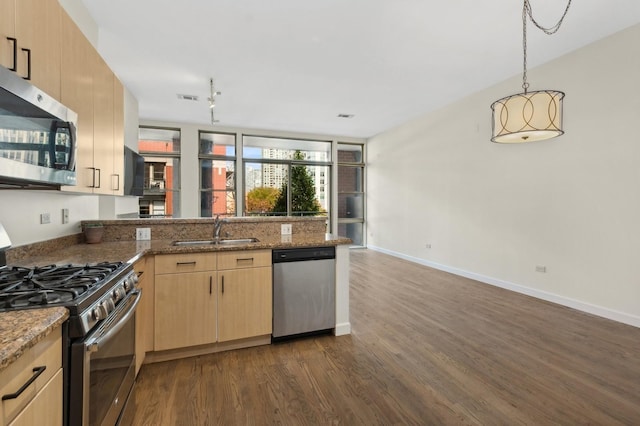 kitchen with stone counters, light brown cabinets, stainless steel appliances, and sink