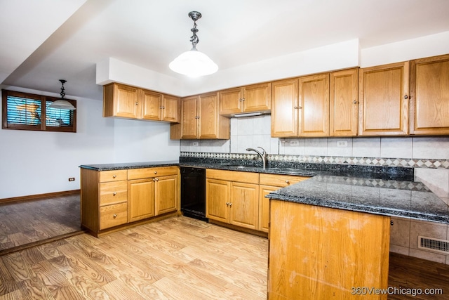 kitchen featuring sink, light hardwood / wood-style flooring, backsplash, dark stone counters, and decorative light fixtures