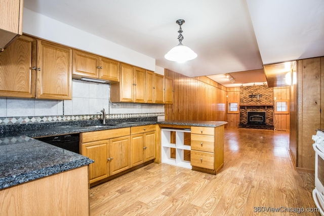 kitchen featuring pendant lighting, dishwasher, sink, dark stone countertops, and a fireplace