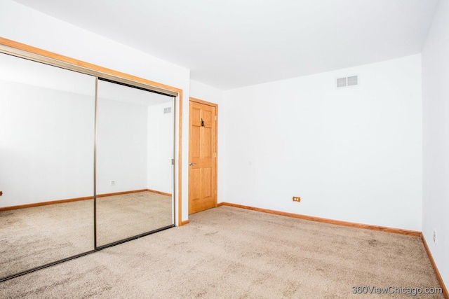 unfurnished bedroom featuring light carpet and a closet