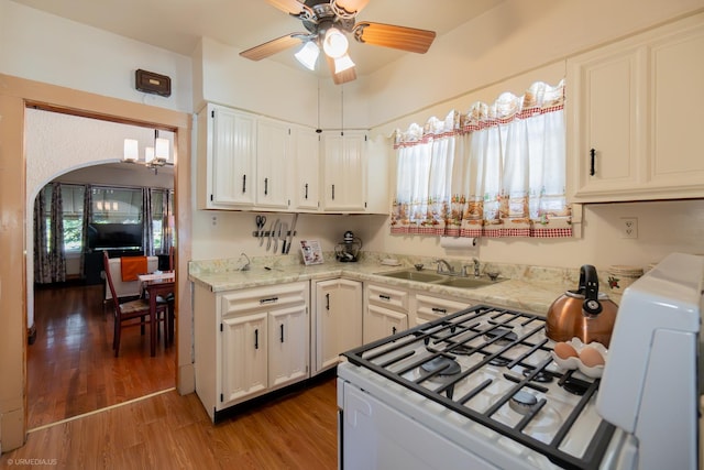 kitchen featuring white cabinetry, gas range gas stove, ceiling fan, a healthy amount of sunlight, and hardwood / wood-style flooring