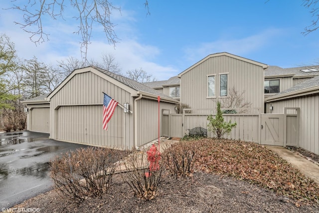 view of front of home featuring aphalt driveway, roof with shingles, a garage, and fence