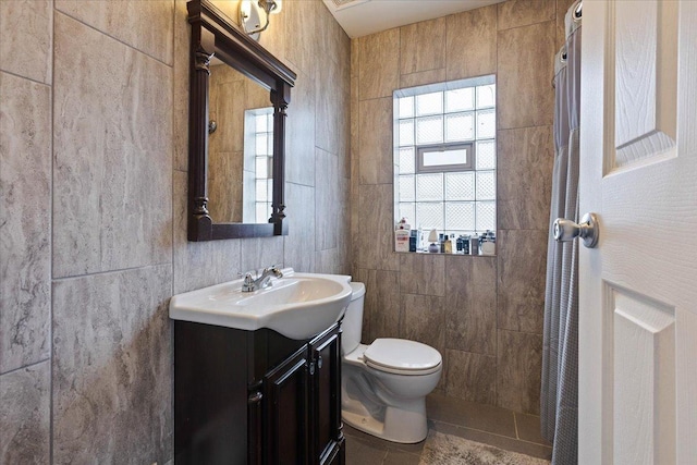 bathroom featuring walk in shower, toilet, tile walls, vanity, and tile patterned flooring