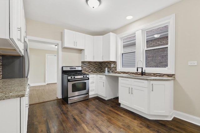 kitchen with gas range, light stone counters, sink, and white cabinets