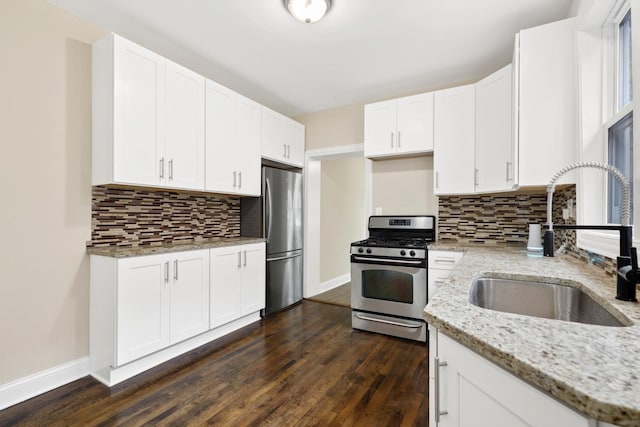 kitchen featuring light stone countertops, sink, stainless steel appliances, tasteful backsplash, and white cabinets